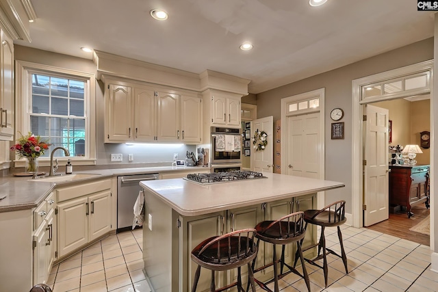 kitchen featuring light tile patterned floors, a center island, stainless steel appliances, a breakfast bar, and sink