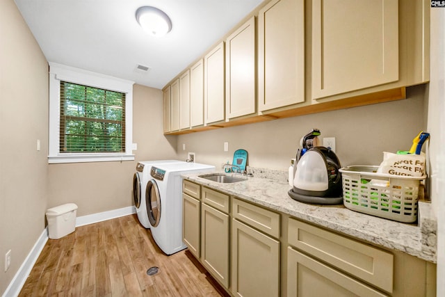 clothes washing area with cabinets, washer and clothes dryer, sink, and light hardwood / wood-style floors