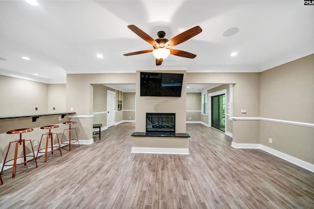 living room featuring light wood-type flooring, ceiling fan, and a large fireplace