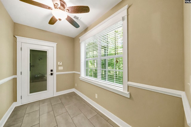 doorway featuring ceiling fan and light tile patterned flooring