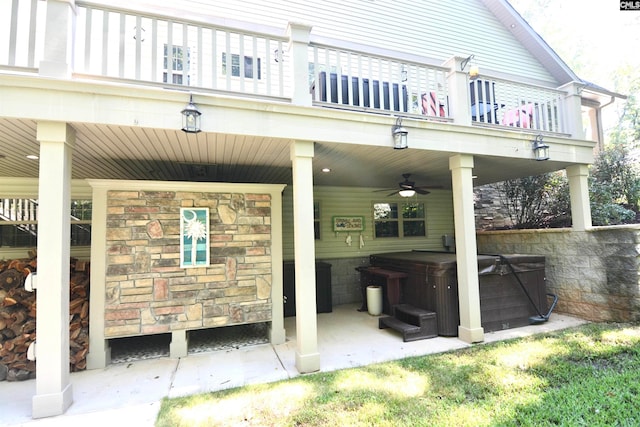 rear view of property featuring a balcony, a hot tub, and ceiling fan