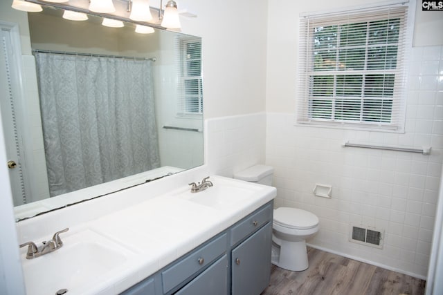 bathroom featuring a shower with shower curtain, toilet, tile walls, wood-type flooring, and vanity