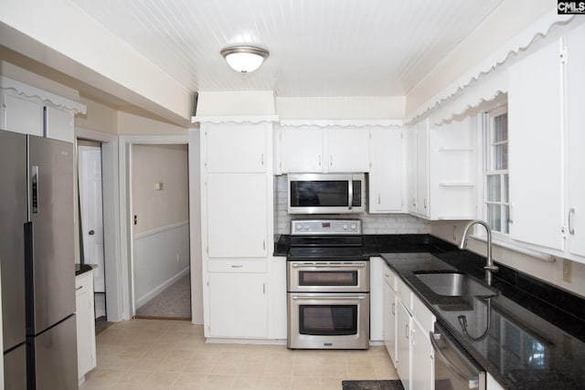 kitchen featuring dark stone counters, sink, appliances with stainless steel finishes, and white cabinetry