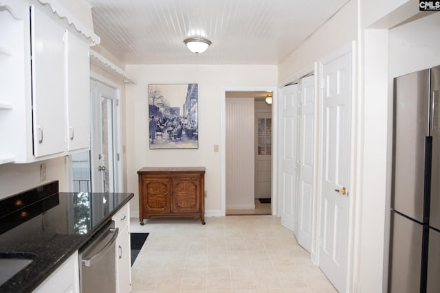 kitchen featuring appliances with stainless steel finishes, dark stone counters, and white cabinetry