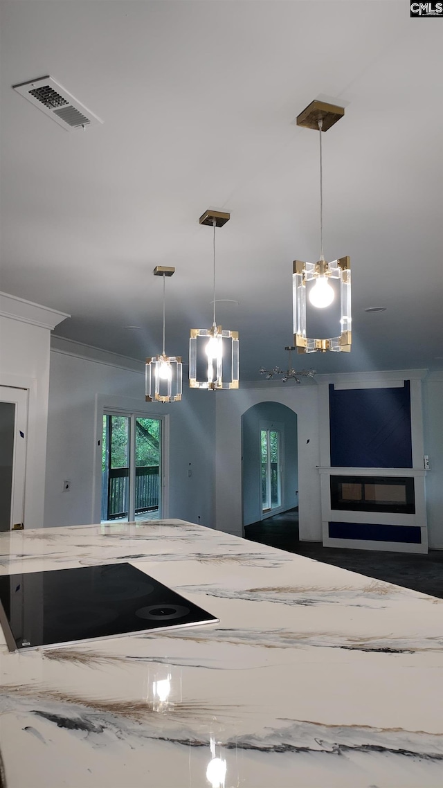 kitchen with ornamental molding, pendant lighting, and light stone countertops