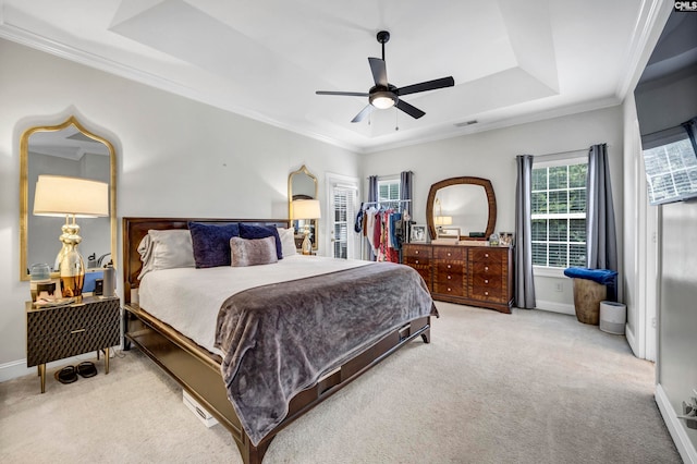 bedroom with ceiling fan, ornamental molding, a tray ceiling, and light colored carpet