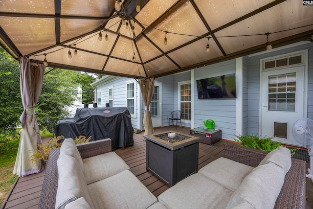 wooden terrace with a gazebo, a grill, and an outdoor living space with a fire pit