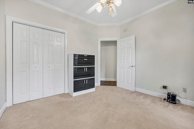 unfurnished bedroom featuring ornamental molding, light colored carpet, a closet, and ceiling fan