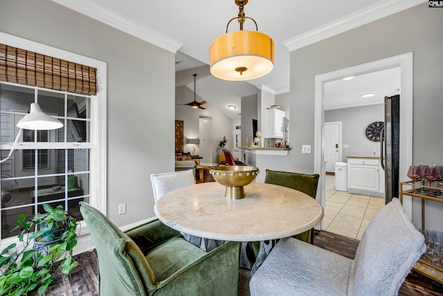 dining space featuring crown molding, light tile patterned flooring, and vaulted ceiling