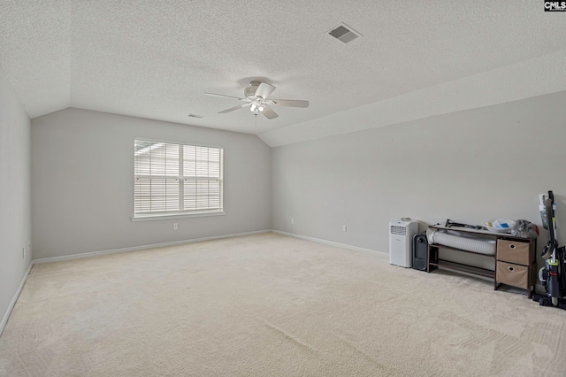 unfurnished room with ceiling fan, a textured ceiling, light carpet, and vaulted ceiling