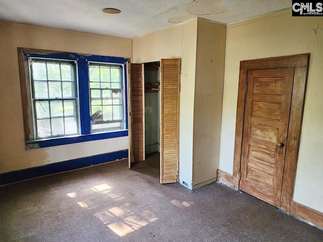 unfurnished bedroom featuring a textured ceiling and dark colored carpet