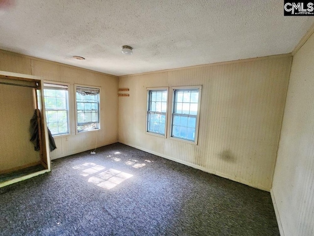 unfurnished bedroom featuring dark colored carpet and a textured ceiling