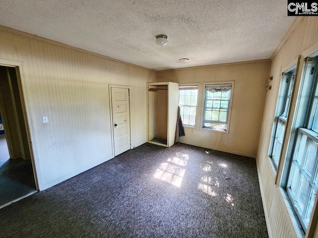 unfurnished bedroom with dark colored carpet and a textured ceiling