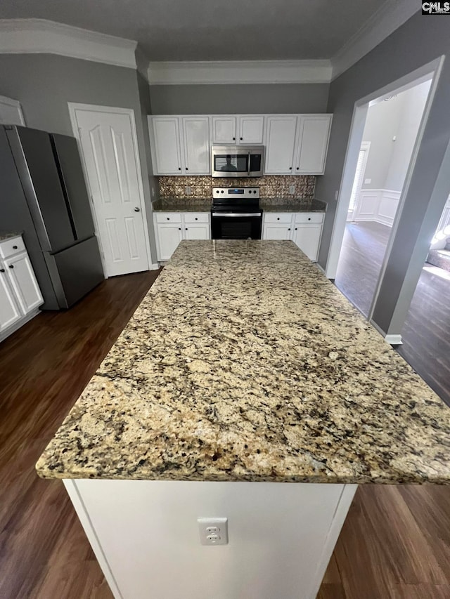 kitchen with crown molding, dark hardwood / wood-style floors, appliances with stainless steel finishes, and white cabinetry