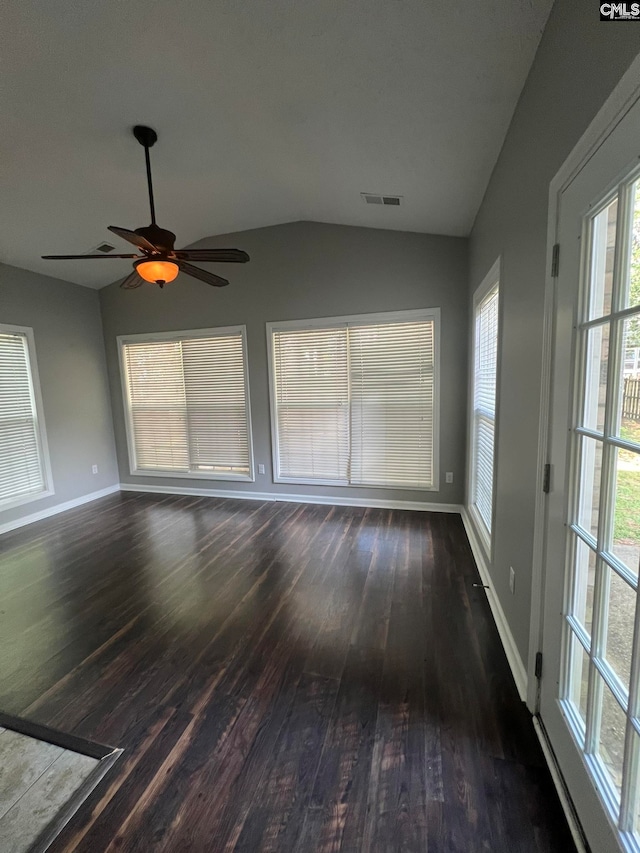 unfurnished living room with dark wood-type flooring, ceiling fan, a wealth of natural light, and vaulted ceiling