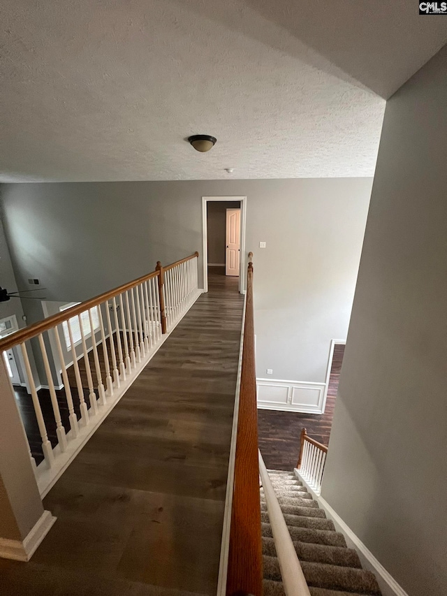 stairway with wood-type flooring and a textured ceiling