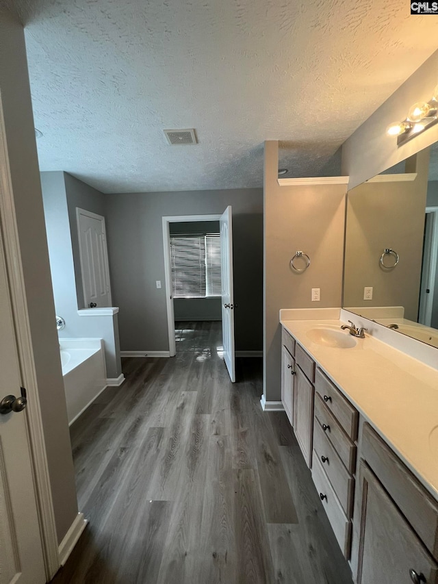 bathroom featuring a tub, hardwood / wood-style flooring, a textured ceiling, and vanity