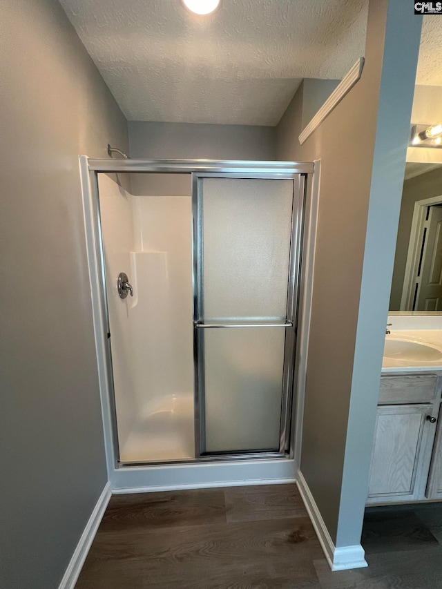 bathroom with vanity, a textured ceiling, wood-type flooring, and an enclosed shower