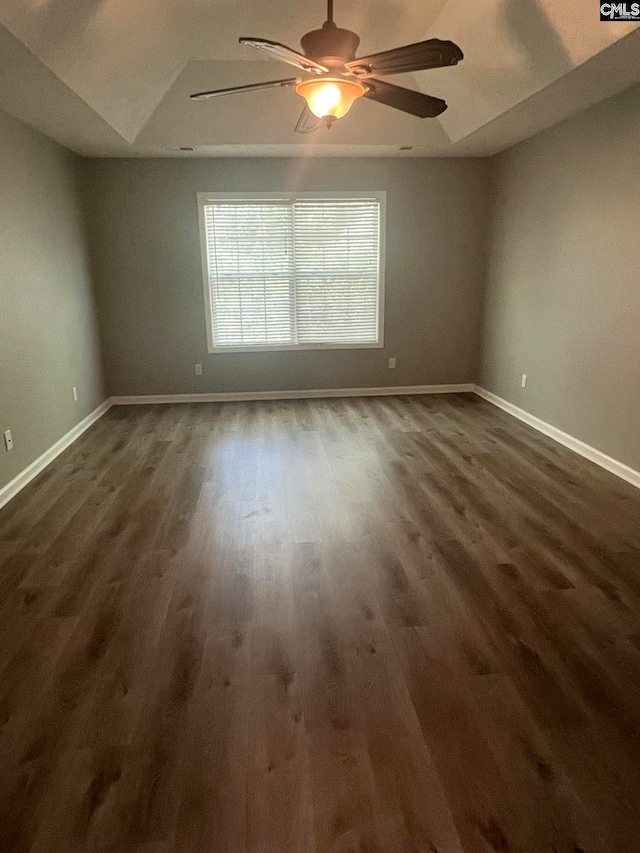 spare room with a tray ceiling, dark hardwood / wood-style flooring, and ceiling fan