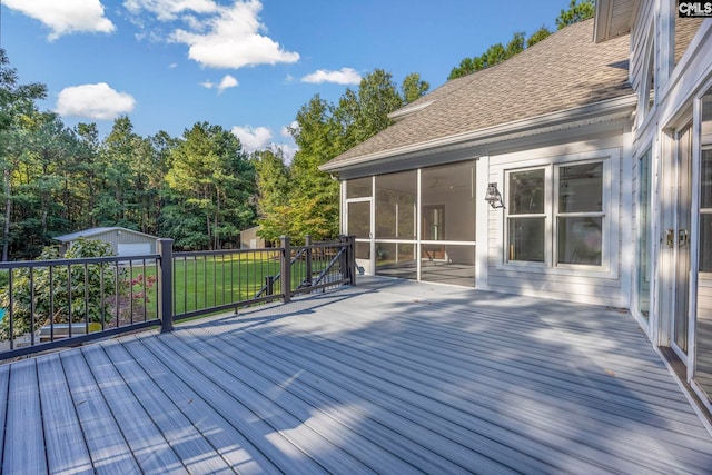 wooden terrace with a lawn, a shed, and a sunroom