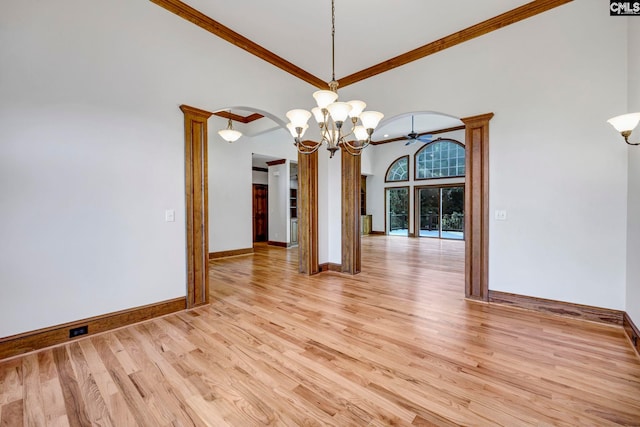 spare room with light wood-type flooring, ornamental molding, a towering ceiling, and a notable chandelier