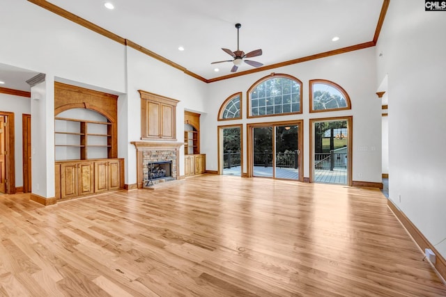 unfurnished living room featuring built in shelves, ceiling fan, light hardwood / wood-style floors, and ornamental molding