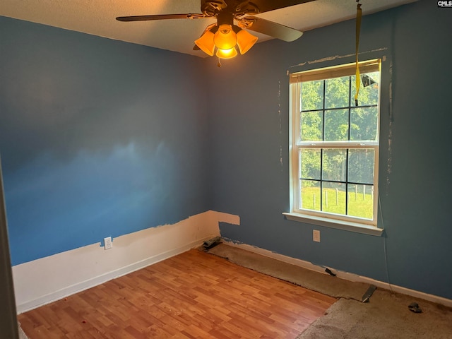 spare room featuring a textured ceiling, a wealth of natural light, light hardwood / wood-style flooring, and ceiling fan