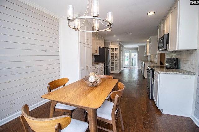 dining room with a chandelier, wooden walls, dark hardwood / wood-style flooring, and ornamental molding