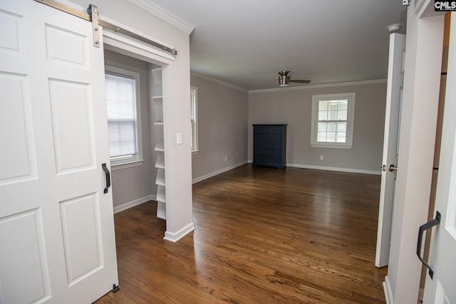 unfurnished living room featuring a barn door, ceiling fan, ornamental molding, and dark wood-type flooring