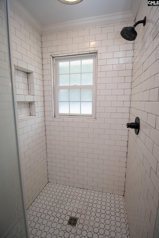 bathroom featuring ornamental molding and a tile shower