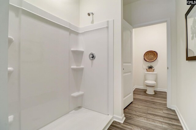 bathroom featuring walk in shower, hardwood / wood-style floors, and toilet