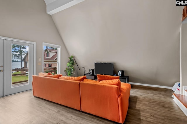 living room featuring wood-type flooring, beam ceiling, and high vaulted ceiling