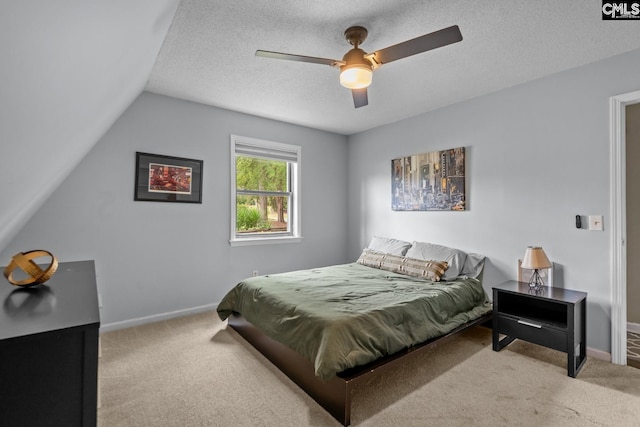 bedroom with vaulted ceiling, ceiling fan, light colored carpet, and a textured ceiling