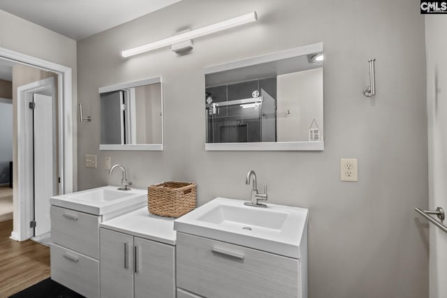 bathroom with wood-type flooring, vanity, and a shower with door