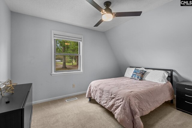 carpeted bedroom featuring a textured ceiling, lofted ceiling, and ceiling fan