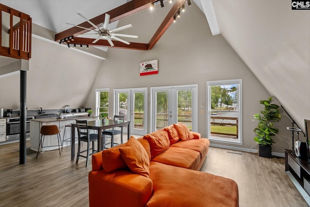 living room with light wood-type flooring, beamed ceiling, high vaulted ceiling, ceiling fan, and french doors