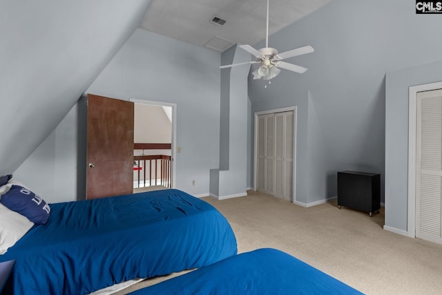 bedroom featuring two closets, lofted ceiling, ceiling fan, and carpet flooring