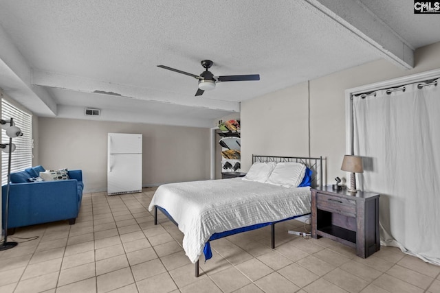 bedroom with a textured ceiling, light tile patterned floors, ceiling fan, and white fridge