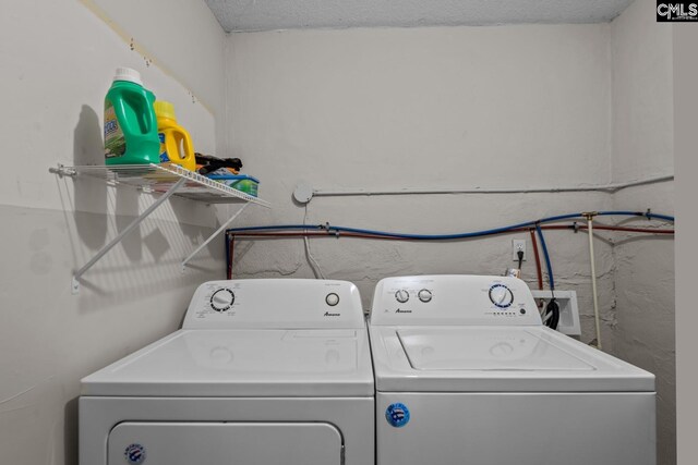 clothes washing area with a textured ceiling and washer and dryer