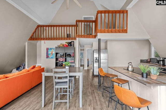 interior space featuring light wood-type flooring, ceiling fan, and high vaulted ceiling