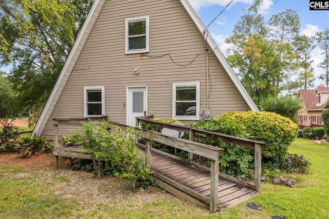 back of property featuring a deck and a yard