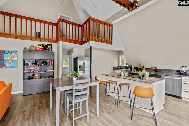 kitchen featuring high vaulted ceiling, beamed ceiling, light hardwood / wood-style floors, and appliances with stainless steel finishes