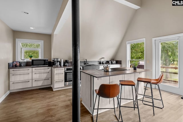 kitchen featuring light wood-type flooring, stainless steel appliances, plenty of natural light, and white cabinetry