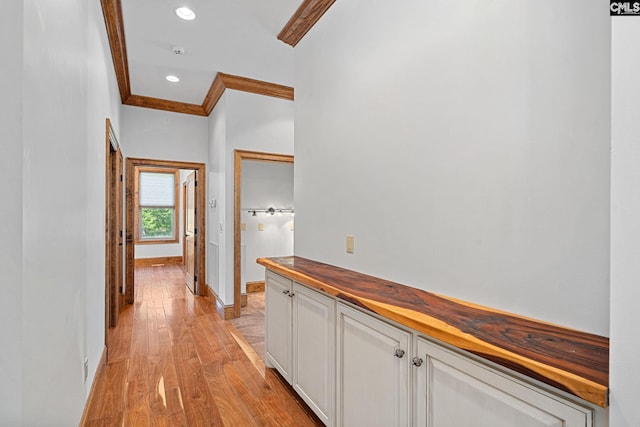 corridor with light wood-type flooring and crown molding