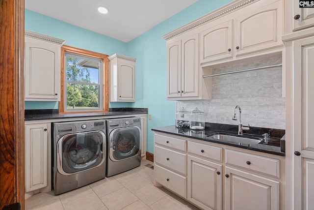 washroom with light tile patterned floors, sink, washer and dryer, and cabinets