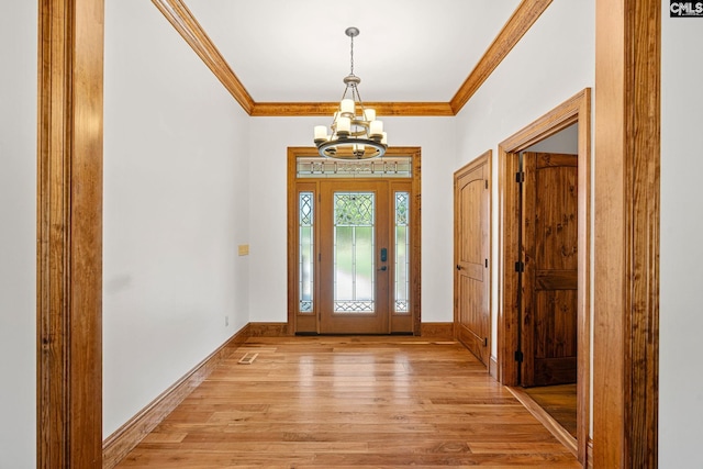 entryway featuring ornamental molding, light wood-type flooring, and a chandelier