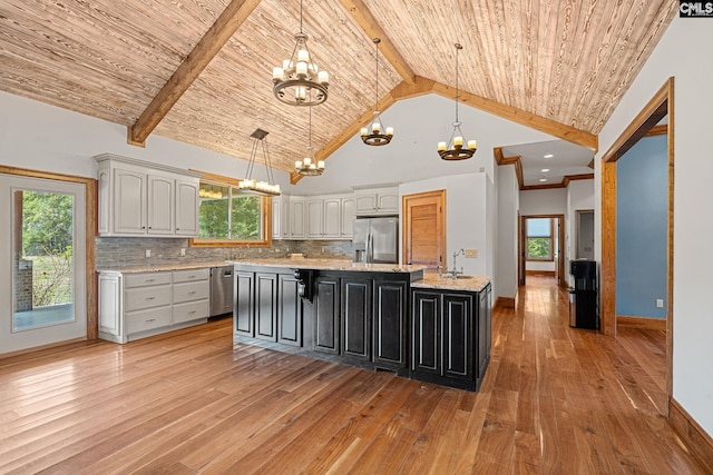 kitchen featuring a notable chandelier, appliances with stainless steel finishes, beam ceiling, and a center island