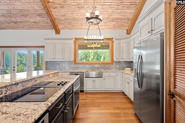 kitchen with a healthy amount of sunlight, vaulted ceiling with beams, stainless steel fridge with ice dispenser, and a chandelier