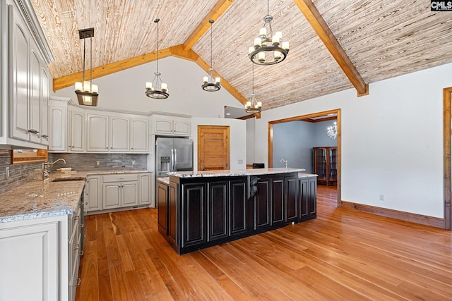 kitchen with beamed ceiling, a kitchen island, high vaulted ceiling, decorative light fixtures, and stainless steel fridge