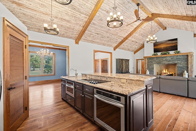 kitchen featuring hanging light fixtures, a fireplace, an inviting chandelier, and stainless steel oven